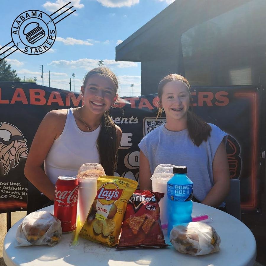 Two friends with burgers, chips and drinks