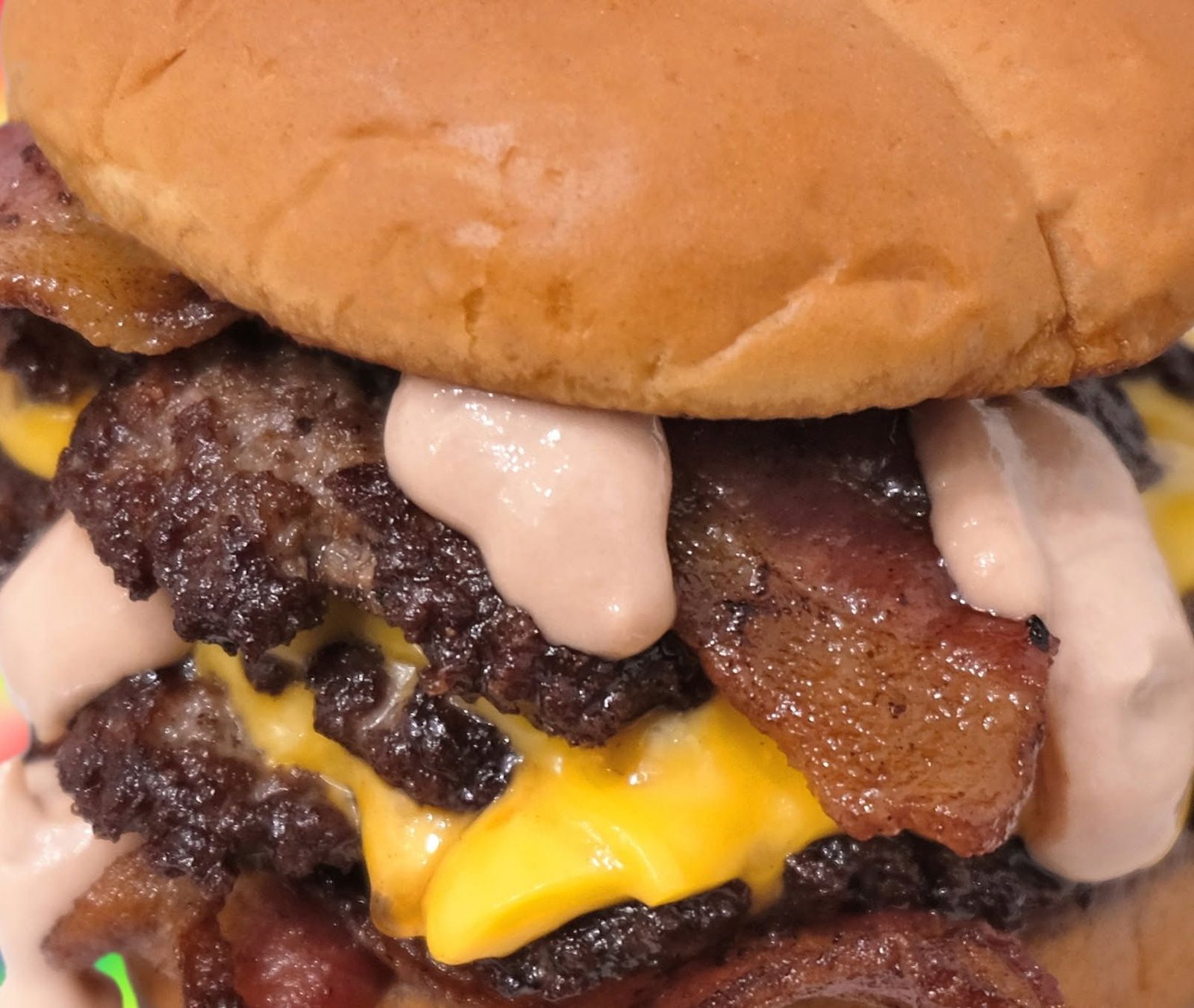 A double smash burger stacked with American cheese, thick-cut bacon and Stacker Sauce